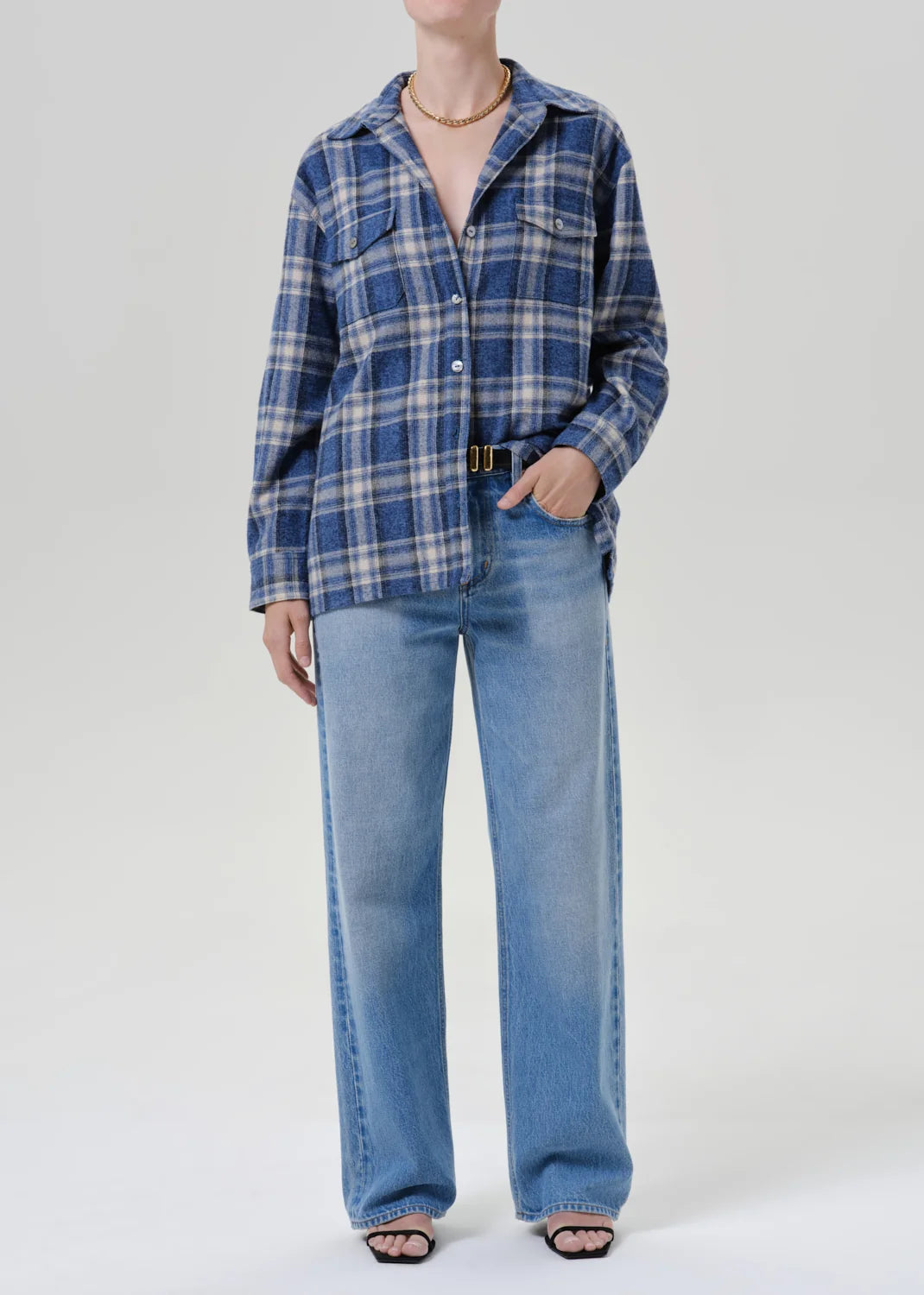 Woman in a marina plaid vintage long button-up shirt by Citizens of Humanity, wide-leg jeans, and black sandals.