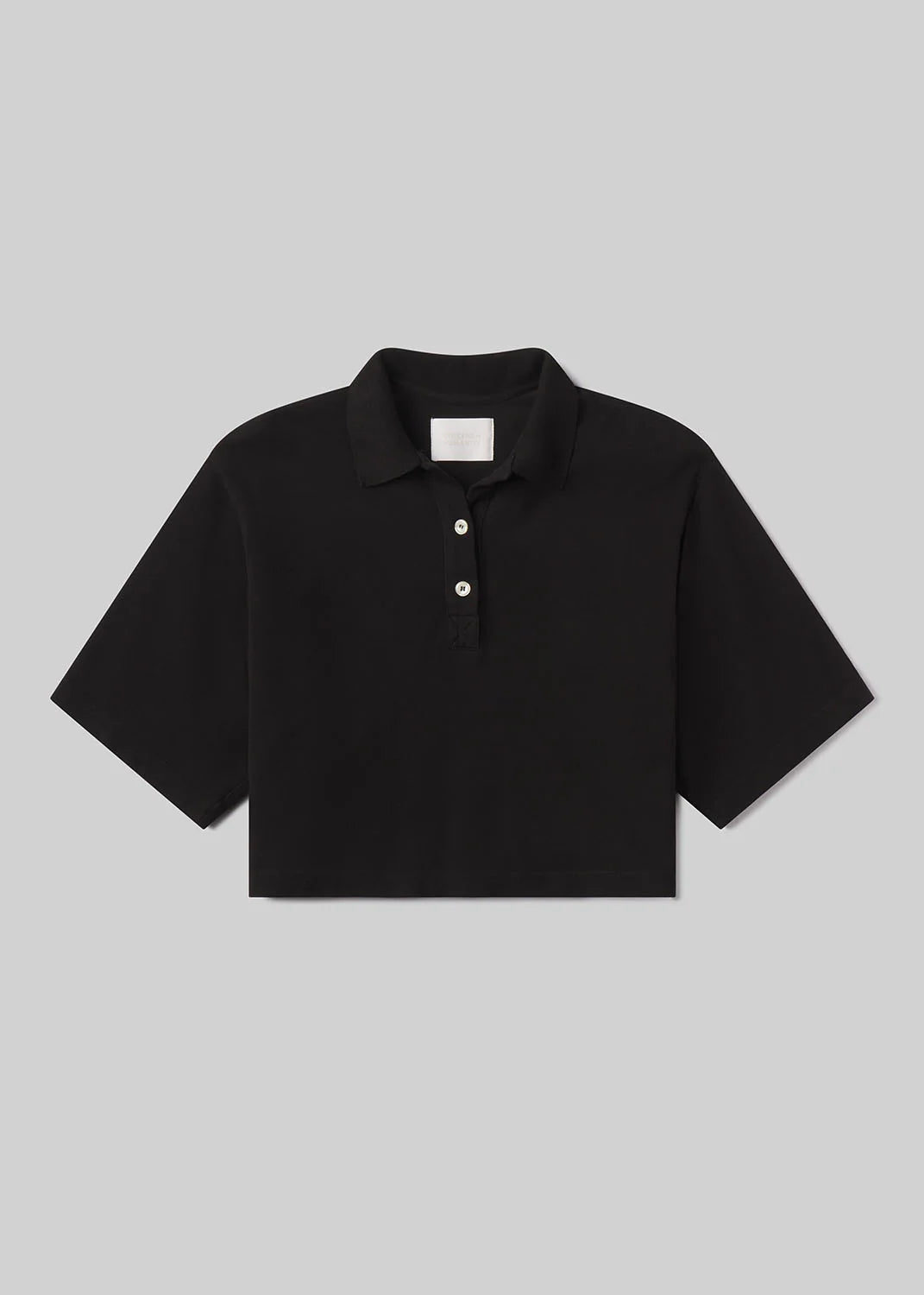 The Lowen polo shirt by Citizens Of Humanity/AGOLDE is a black cropped Supima jersey top with short sleeves, a collar, and three white buttons on the placket, shown against a light gray background.