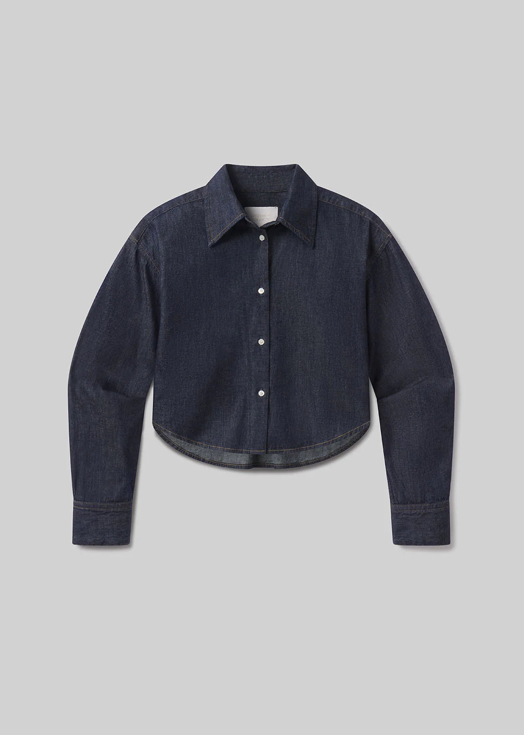 The Ana Cropped Shirt in Piave by Citizens Of Humanity/AGOLDE features a dark indigo hue, long sleeves, a collar, and button-down front, crafted from premium Japanese denim and shown on a light gray background.