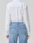 A person is shown from the back wearing the avni slim shirt in blue micro stripe by Citizens Of Humanity/AGOLDE, paired with high-waisted light blue jeans, set against a plain gray background.