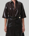 A person wearing the Frances Leather Cropped Cape by Citizens Of Humanity/AGOLDE, styled with a wide black belt featuring a large rectangular gold buckle.