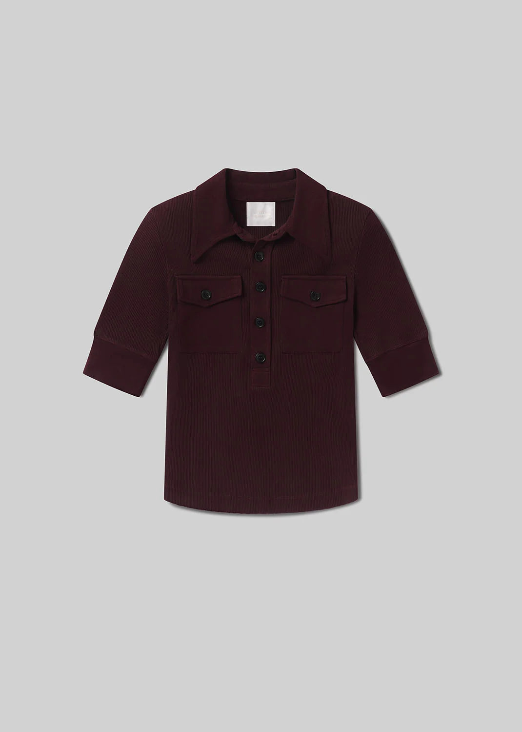 The Amina Polo Shirt by Citizens Of Humanity/AGOLDE is a maroon ribbed cotton long-sleeve shirt with a collar, black front buttons, and two chest patch pockets, shown on a light grey background.