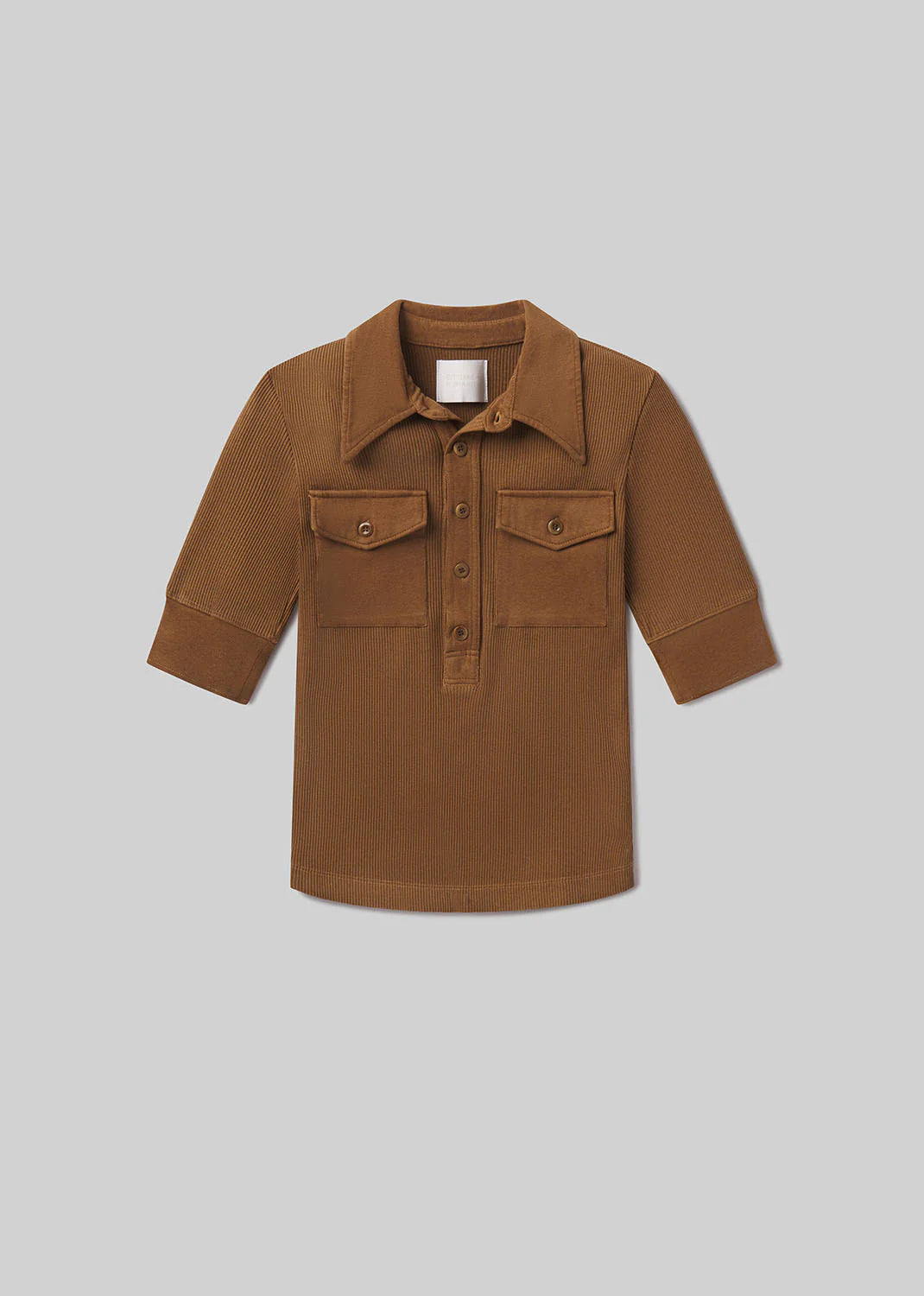 The Amina Polo Shirt by Citizens Of Humanity/AGOLDE features long sleeves, brown ribbed cotton, a wide collar, two front flap pockets, and a partial button placket, shown laid flat on a light gray background.