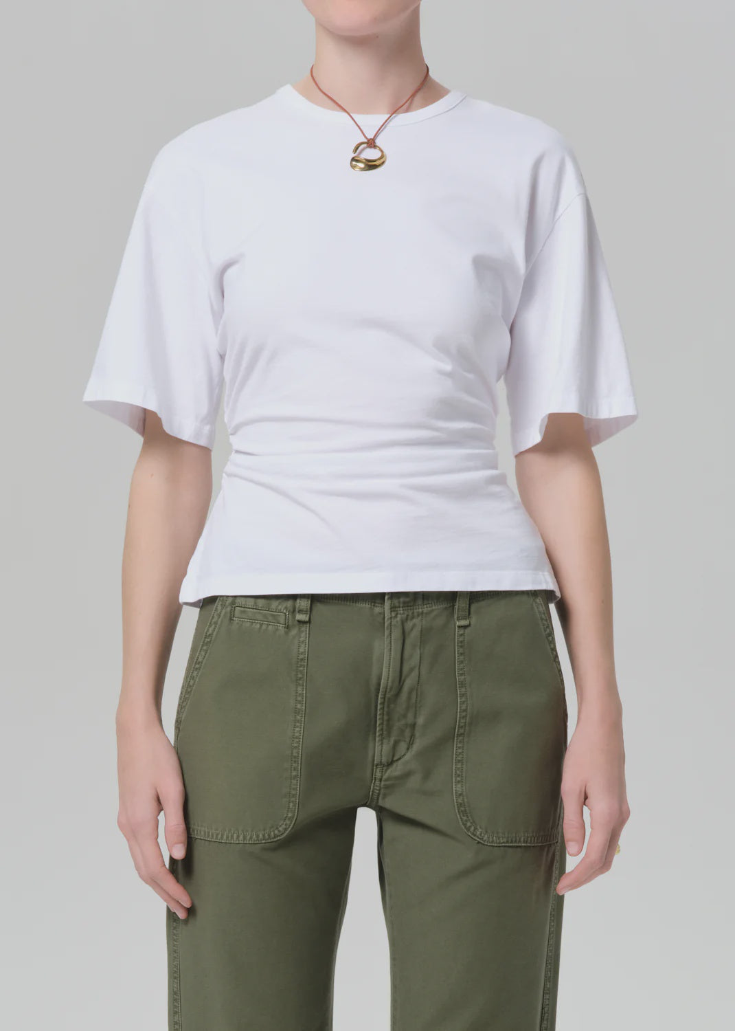 Model wearing the fabien tee by Citizens Of Humanity/AGOLDE, paired with olive green pants and a gold pendant necklace, shot from shoulders to hips against a plain light gray background.