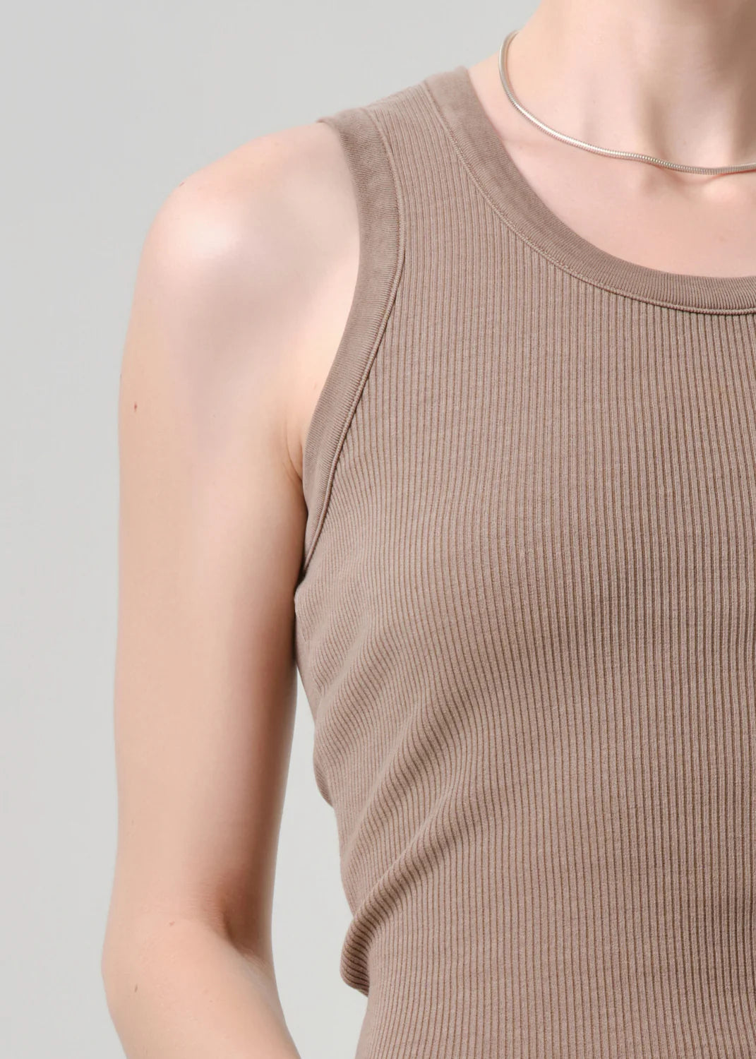 A person wears the nova tank by Citizens Of Humanity/AGOLDE—an organic cotton ribbed tank with a scoop neckline—paired with a thin silver necklace, photographed from shoulders to waist against a plain light background.