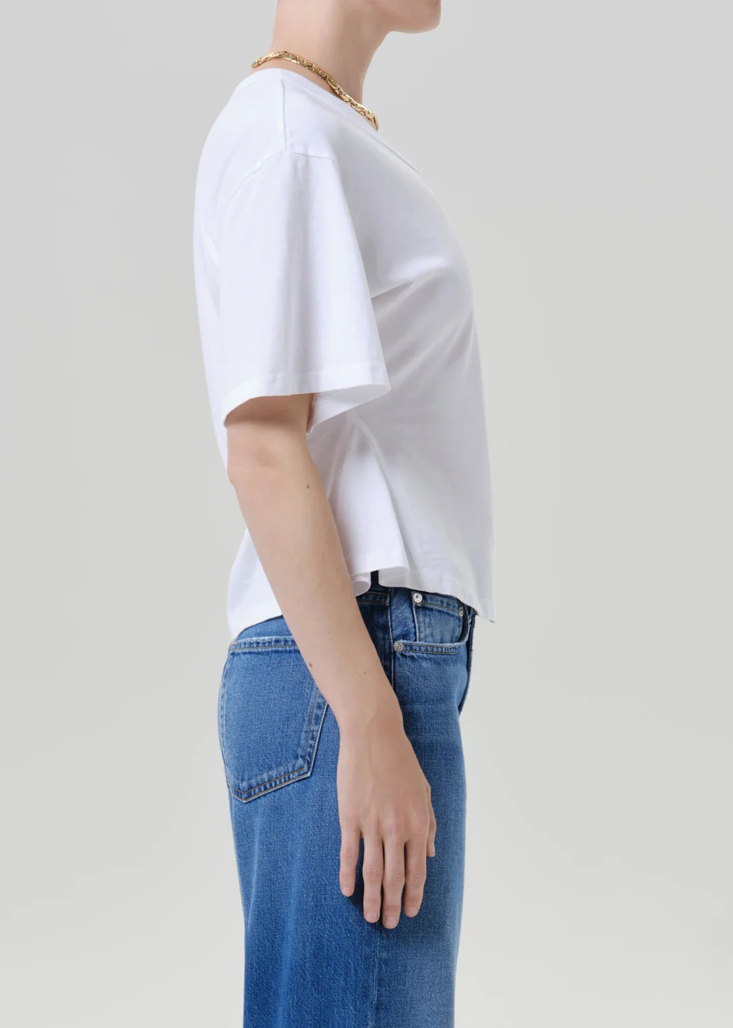 Rework mens tee by Citizens Of Humanity/AGOLDE in white, paired with blue jeans, casual look against light grey backdrop.