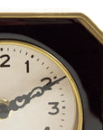 Close-up of the Zentique Black and Gold Clock, a vintage-style octagonal table clock with white dial, black hour marks, and gold accents. Its dark, angular border makes it a striking piece for elegant décor. Shows time at 10:10.