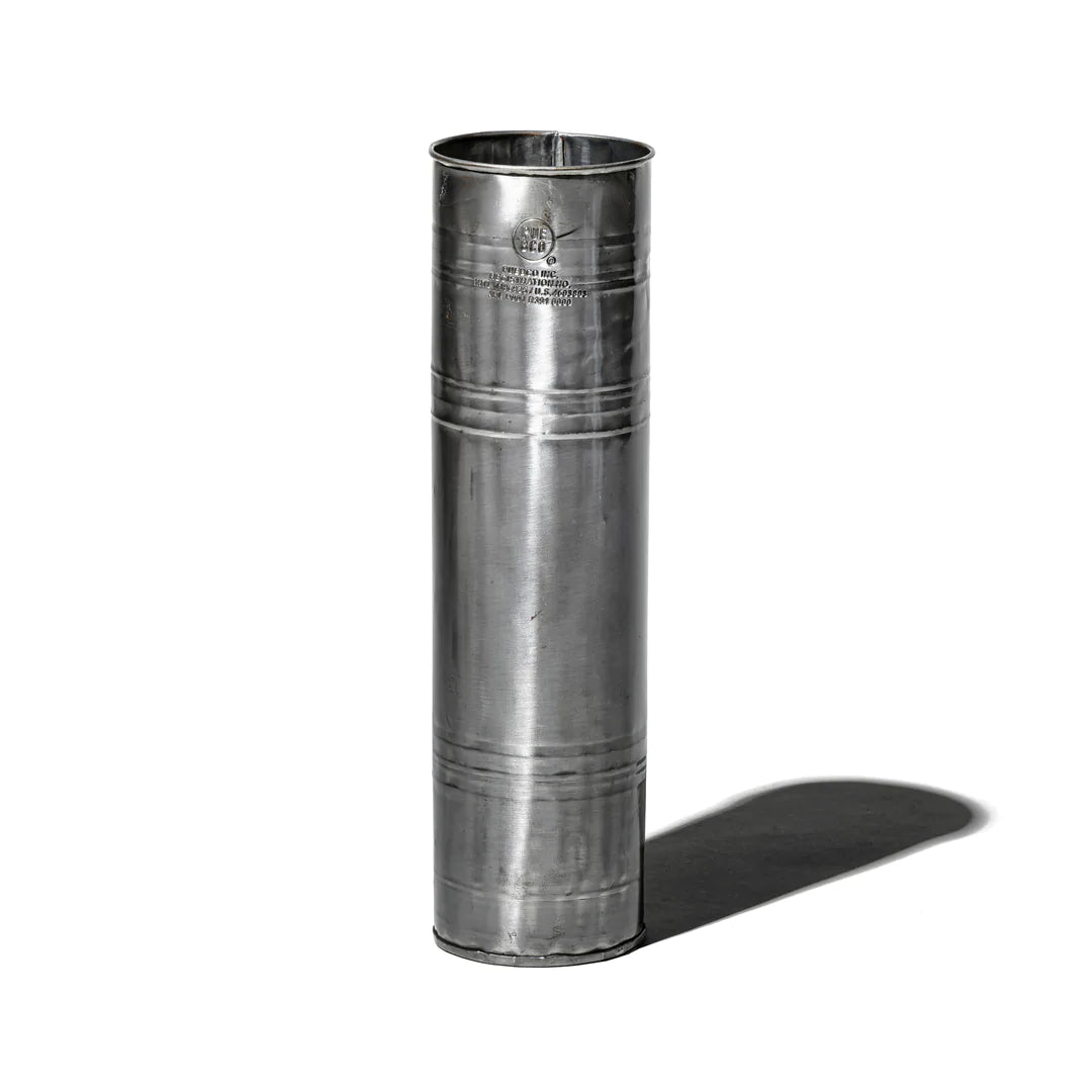 The Faire Steel Trashcan, tall and cylindrical with a smooth, reflective surface, stands upright on a white background and casts a distinct shadow to the right.
