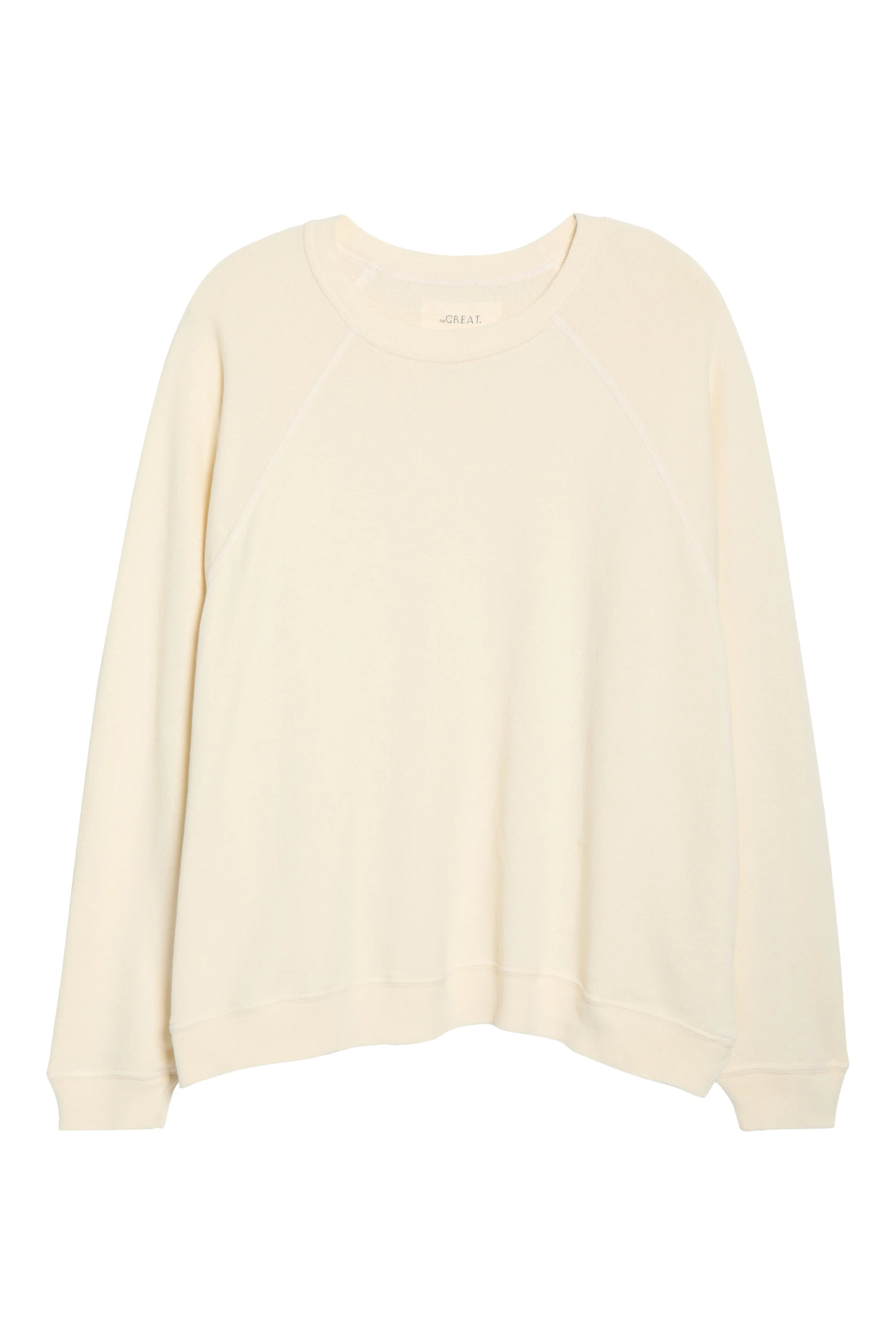 The Rehearsal Sweatshirt by The Great Inc. is an off-white, long-sleeve crewneck with raglan sleeves, displayed flat on a white background. Made in the USA from breathable cotton, this casual design features a simple look with no visible logos or patterns.