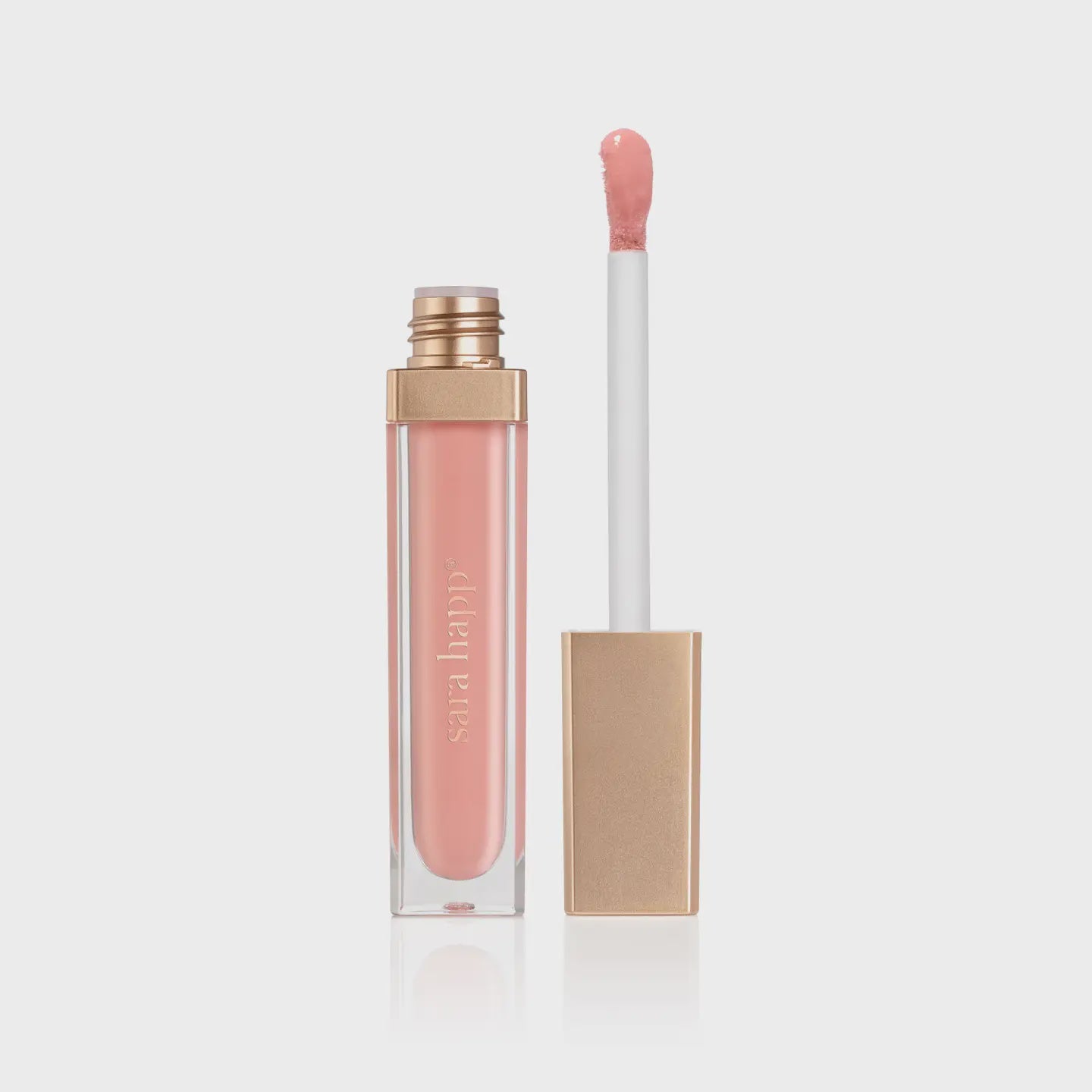 The Hydrating Lip Gloss from Faire features a pink gloss infused with jojoba oil. It has a gold cap and clear tube displaying the brand in white. The Lip Slip offers sheer color that stands out against a light gray background.