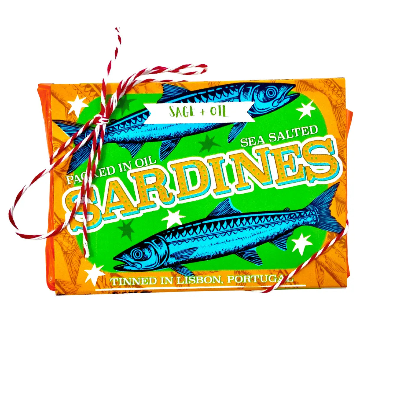 The Sardine Tin Luxury Soap by Faire resembles a colorful sardine tin with green and orange packaging and sardine illustrations. It is tied with red and white string, labeled "Packed in Oil, Sea Salted Sardines, Tinned in Lisbon, Portugal." Discover its unique charm today!.