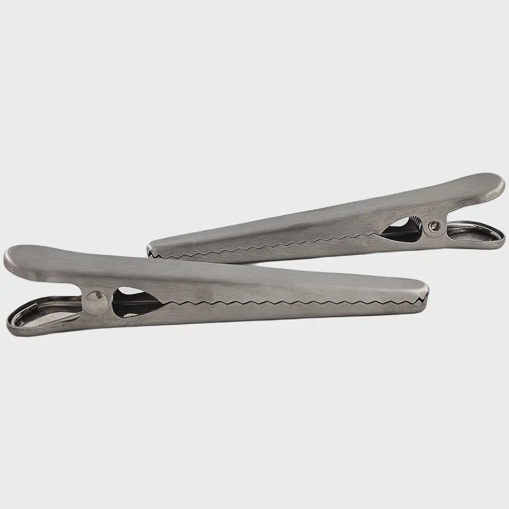 Two Faire Stainless Steel Kitchen Bag Clips with serrated edges are positioned parallel to each other on a plain background. These clips boast a classic design and include a spring mechanism for gripping.