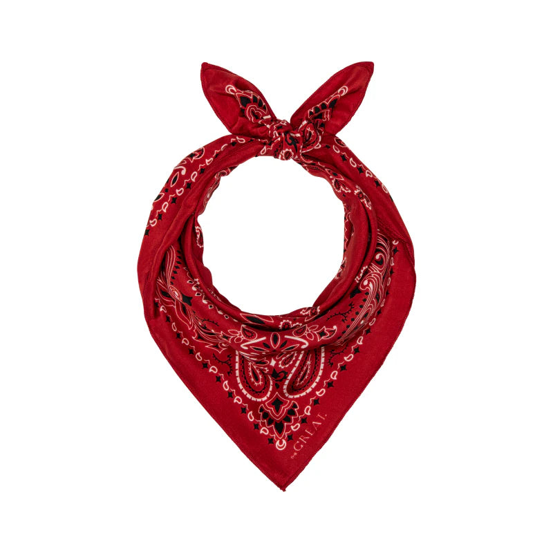 The Silk Bandana by The Great Inc. features soft red silk with a paisley pattern in black and white on a white background, tied in a knot at the top to form a loop.