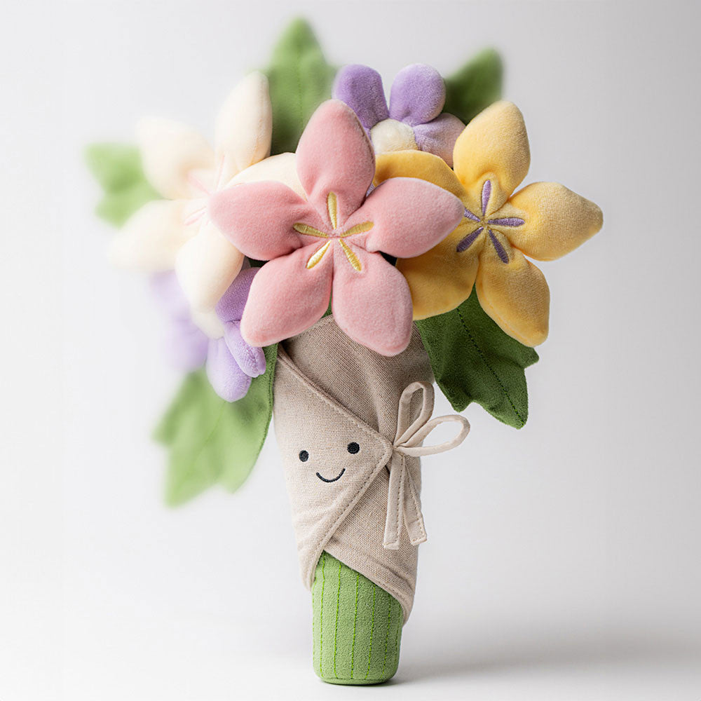 Jelly Cat Inc.’s Bouquet of Flowers features soft pastel blooms in pink, yellow, and purple with green leaves, wrapped in beige fabric with a bow. The plush bouquet has a smiling face, making it an adorable and playful gift.