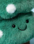 Close-up of the Jelly Cat Inc. Amuseables Christmas Tree plush, shaped like a bush with white fluffy spots, black bead eyes, and a stitched smile on a light blue background—perfect festive decor!.