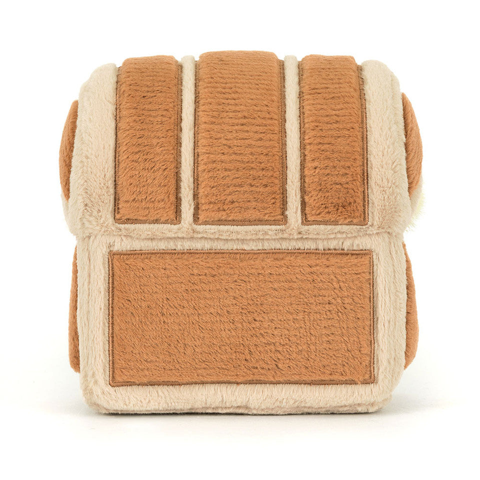 The "Treasure Chest" plush by Jelly Cat Inc. is a soft, brown and beige sandwich bread crust-shaped toy with fuzzy texture and rectangular sections, resembling a treasure chest, displayed against a white background.
