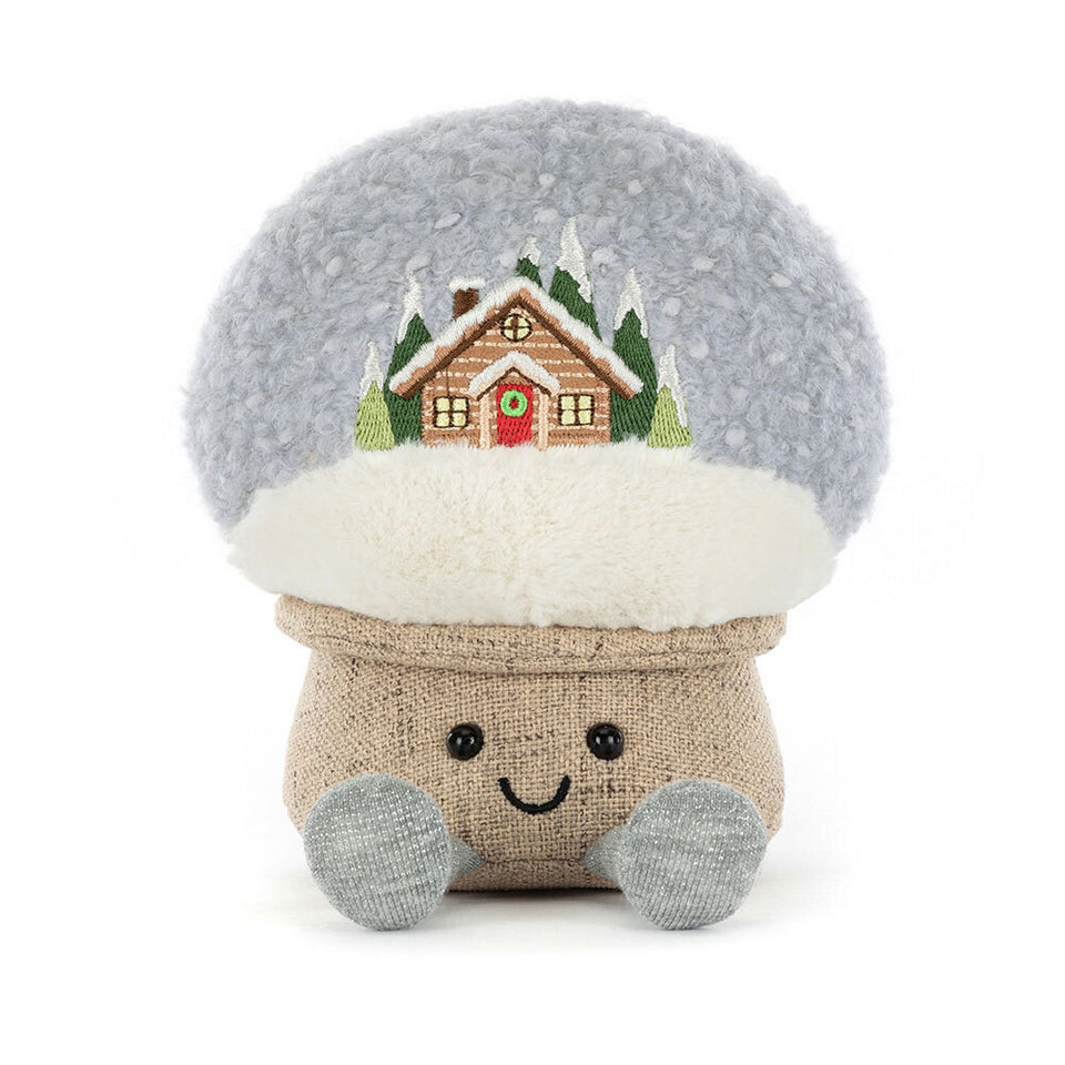 The Jelly Cat Inc. Amuseables Snow Globe is a plush mushroom toy with a fluffy cap, embroidered cabin and pine trees, smiley face, round black eyes, and gray feet—a whimsical après ski or ski gift!.