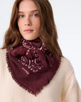KUJTEN Hachiko Bico scarf in deep red styled over a cream ribbed sweater, modern and cozy look.