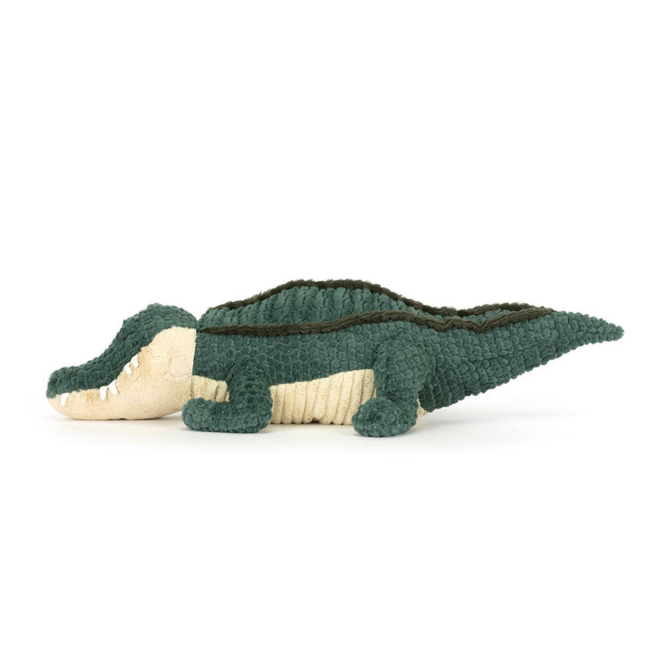 The Allexi Alligator by Jelly Cat Inc. is a soft, green and beige plush toy with textured fabric, shown lying on its stomach in a side profile—a cute tribute to meat-free Southern food on a plain white background.