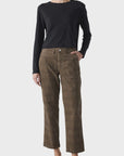 Wearing a black long-sleeve top, AMO Denim's Lillian Plaid Cord wide-leg pants, and black loafers, a person stands against a plain light background with one hand in their pocket.