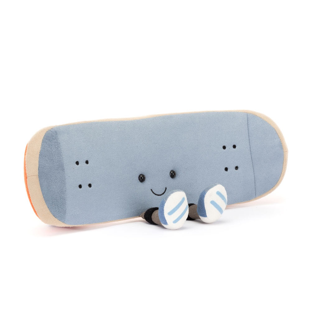 Introducing the Amuseables Skateboard by Jelly Cat Inc., a plush toy designed to resemble a skateboard with a light blue deck, featuring two smiling eyes and a cheerful embroidered smile. It is complete with Amuseables Sports branded blue and white striped sneakers at the bottom.