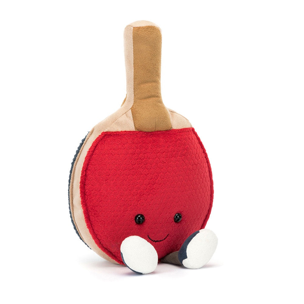 Introducing the Jelly Cat Inc. Amuseables Sports Table Tennis plush toy: This adorable creation is shaped like a table tennis paddle, complete with textured panels and a charming red face. It features an embroidered smile and black eyes, crafted from soft polyester fibers. The toy stands upright on small white feet and has a beige handle, all set against a white background.