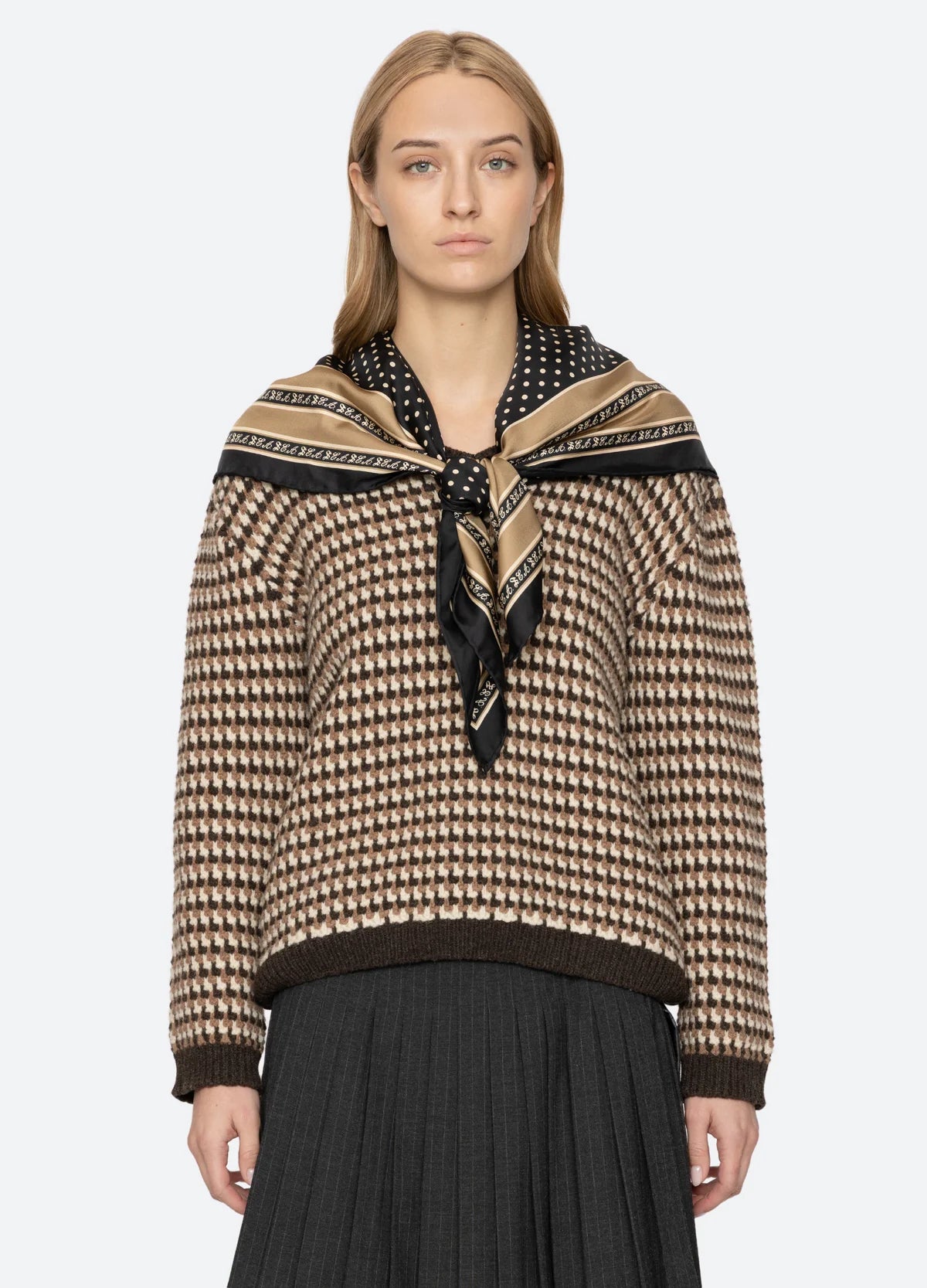 Declan short sleeve polo sweater by Sea New York styled with a black pleated skirt and scarf against a simple backdrop.