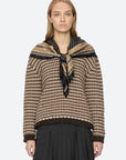 Declan short sleeve polo sweater by Sea New York styled with a black pleated skirt and scarf against a simple backdrop.