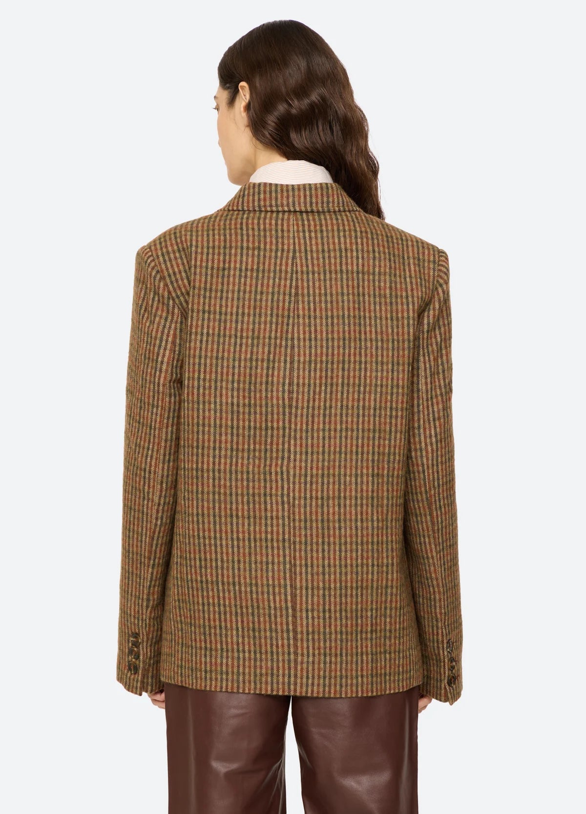 Plaid wool blazer by Sea New York paired with brown leather pants, shown from the back, wavy hair over one shoulder.