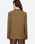Plaid wool blazer by Sea New York paired with brown leather pants, shown from the back, wavy hair over one shoulder.
