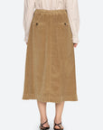 Tan corduroy midi skirt with elastic waist and back pockets by Sea New York, styled with black sandals.