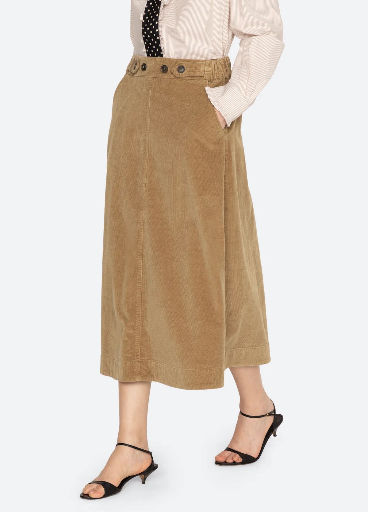 Garrett Corduroy Midi Skirt by Sea New York styled with beige shirt, black tie, and heeled sandals, side view.