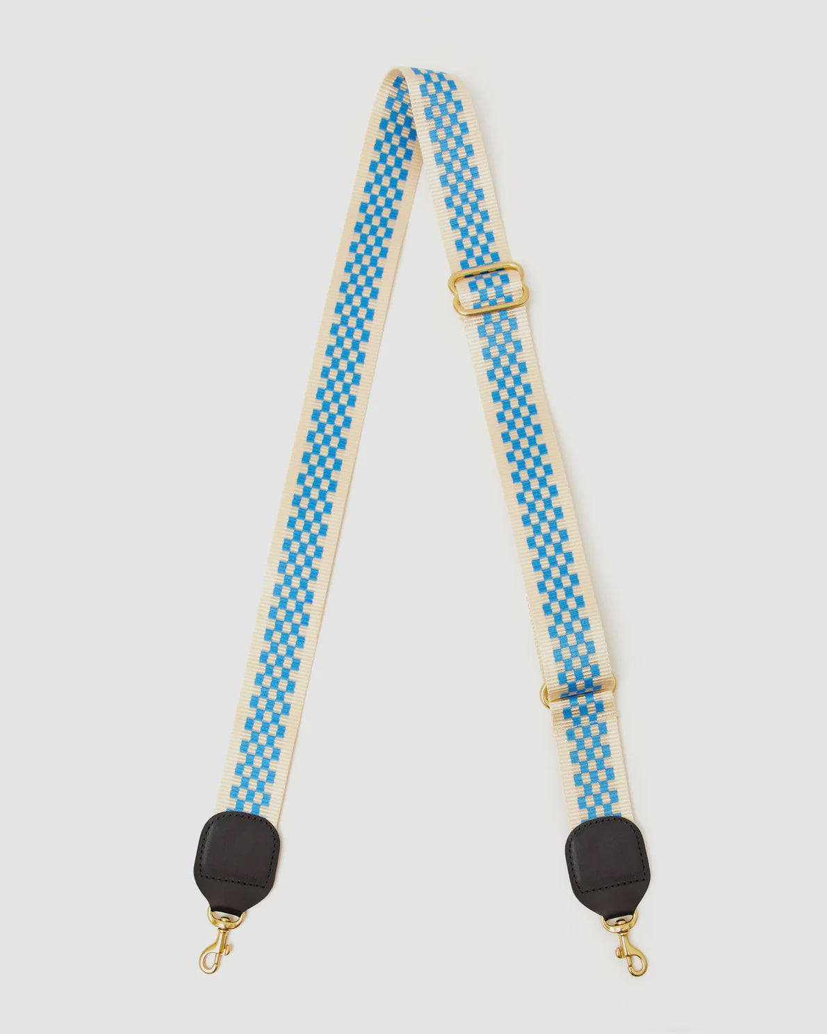 A stylish Clare Vivier Crossbody Strap with a blue and white checkerboard pattern, perfect for your favorite crossbody bag. The strap features black leather ends with gold-tone swivel clasps and an adjustable gold buckle. Made from durable nylon webbing, it ensures both style and longevity on a white background.