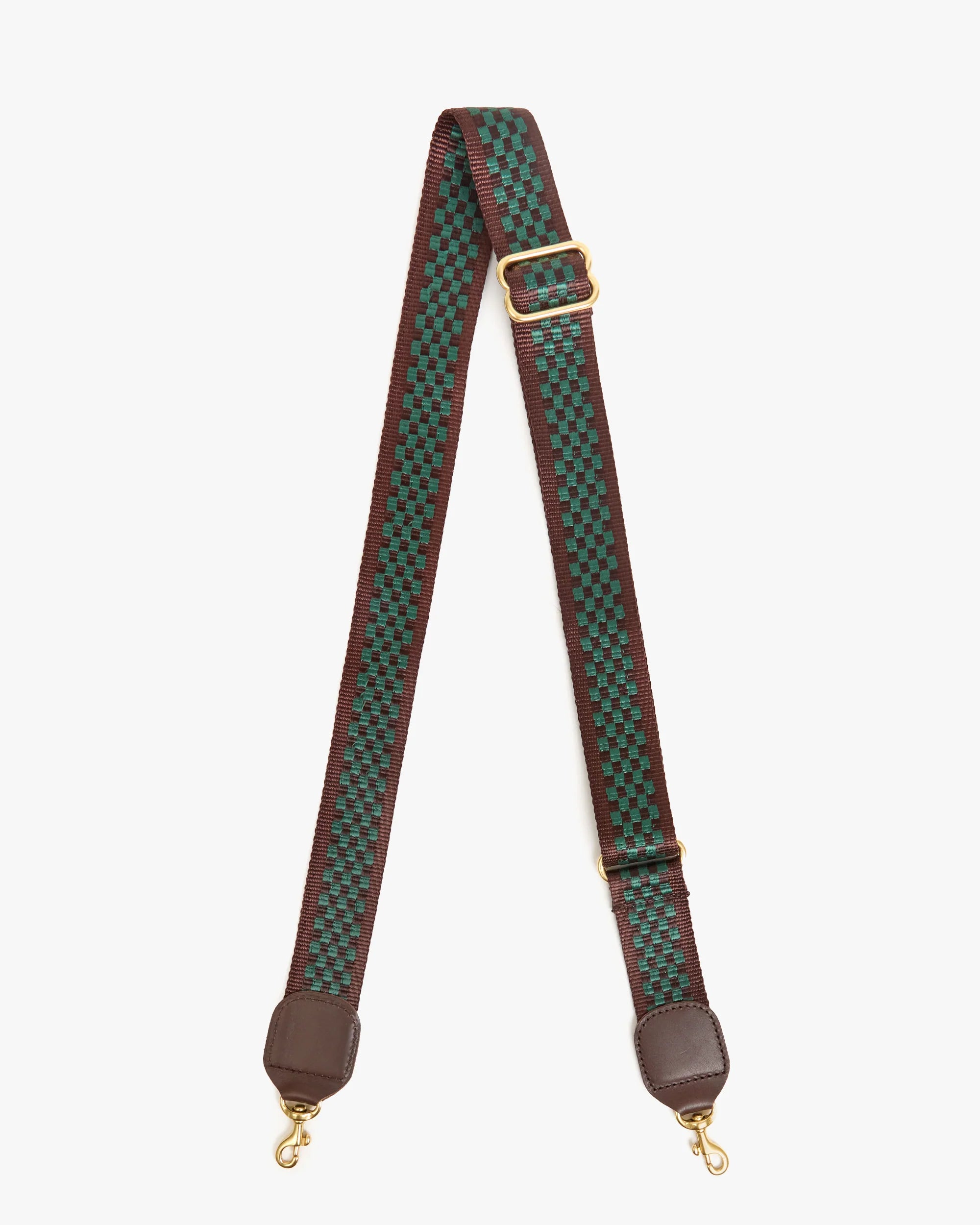 The Clare Vivier Adjustable Crossbody Strap features green and black checkerboard cotton webbing, brown edges, leather ends, an adjustable gold buckle, and gold clasps on both sides.