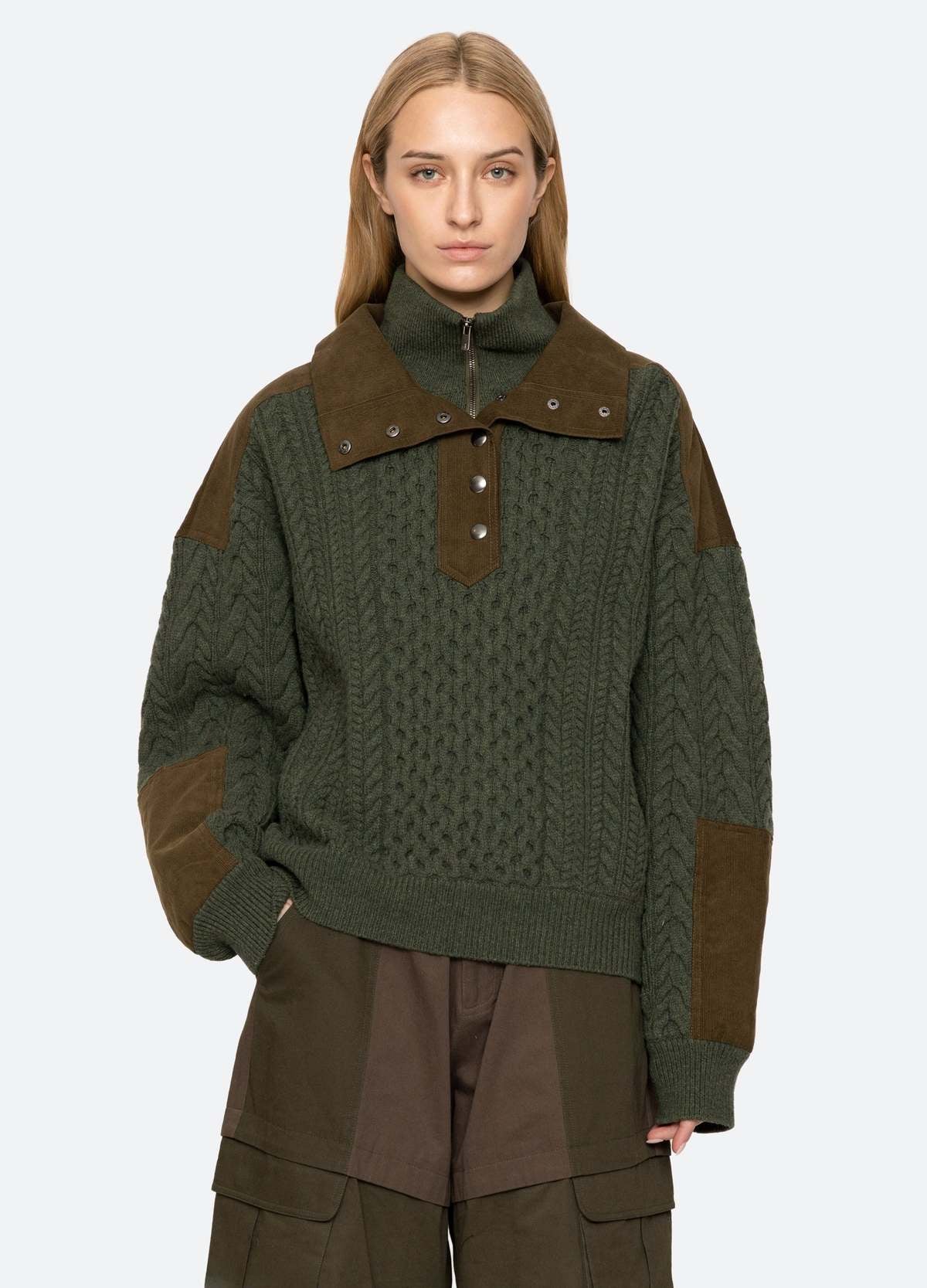 Green cable half zip sweater by Sea New York styled with cargo pants, shown against a plain backdrop.