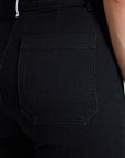 Close-up of a person wearing black Sailor Pants by ASKK, focusing on the back pocket. The Japanese denim material has a slight texture, with visible stitching that emphasizes the pocket's outline against the dark fabric.