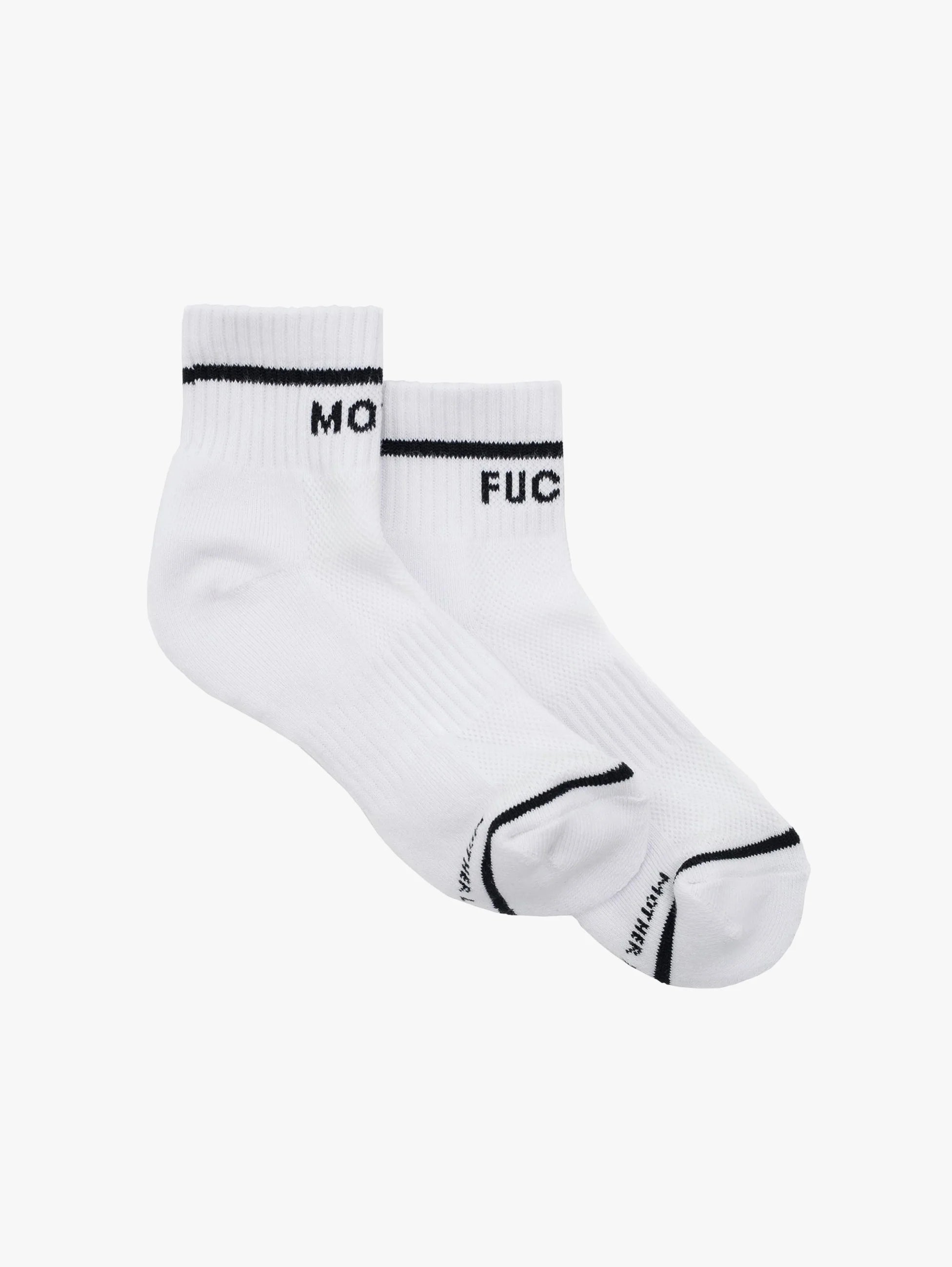 The Mother Baby Steps Ankle socks feature classic black and white tube sock styling, with "MO" on one cuff and "FUC" on the other, shown against a plain white background.