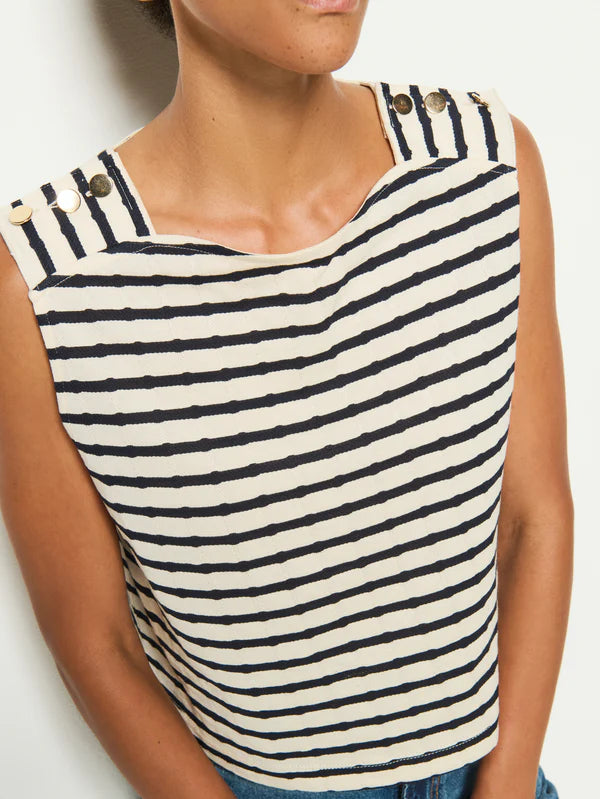 A person wearing the Bettina Tank by Nation LTD, crafted from soft Peruvian cotton with navy and white stripes and gold shank buttons on the shoulders.