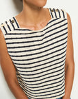 A person wearing the Bettina Tank by Nation LTD, crafted from soft Peruvian cotton with navy and white stripes and gold shank buttons on the shoulders.