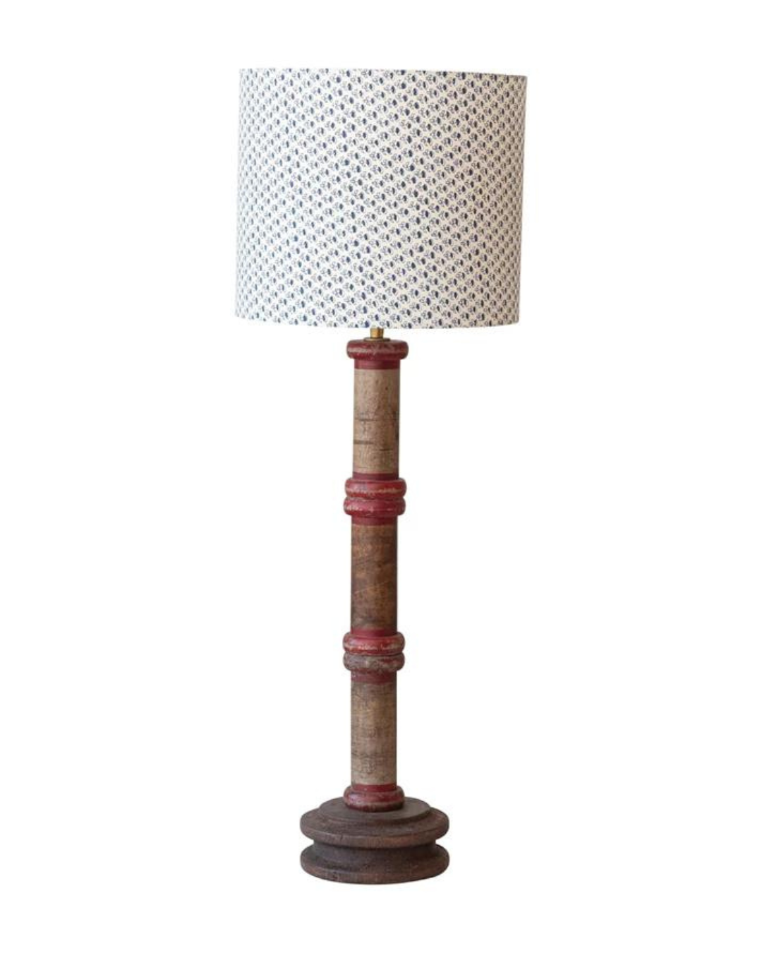 The Spool Table Lamp by Creative Co-op is a rustic wood lamp featuring a cylindrical base with red accents and a distressed finish. It includes a white fabric lampshade decorated with a subtle blue and white geometric pattern, seamlessly blending vintage and contemporary design elements.