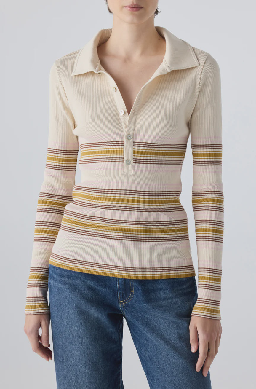 A person wears the AMO Denim Desiree Tee—a cream-colored ribbed top with multicolored horizontal stripes and a classic collar—paired with blue jeans, standing against a plain light background.