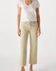 Person wearing a white short-sleeve t-shirt, AMO Denim Billie Pants—relaxed fit cropped wide leg jeans in premium rigid denim—and black heeled sandals, standing against a plain light background.