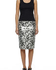 A woman stands facing forward in a sleeveless black tank top, Le Superbe's Black Palms Pencil Skirt with a bold palm print, and black sandals.