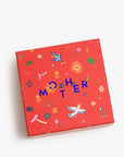 The Mother Burnout Candle by Mother features a vibrant box in blue, orange, and pink with bold "MOTHER" text. Inside is a luxurious three-wick soy wax candle.