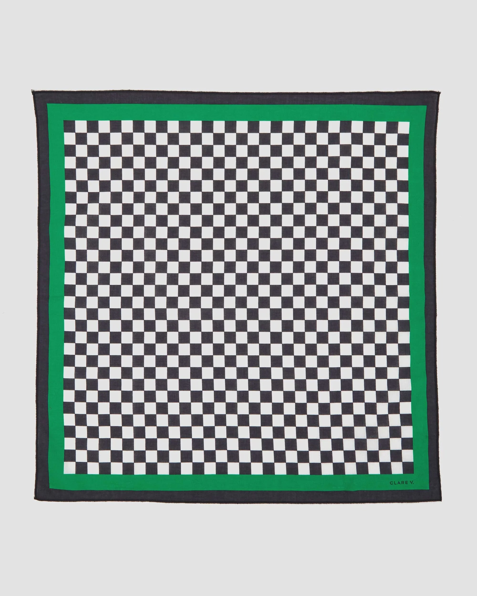 The Clare V Bandana by Clare Vivier is a cotton square scarf with a stylish black and white checkered pattern, bordered by a green and black edge, expertly crafted in India.