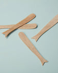 The Be Home Sydney Whale Spreaders S/4 are handcrafted from sustainably sourced mango wood and feature whale-inspired shapes. Arranged on a light blue surface, these unique utensils add charm to any table setting.