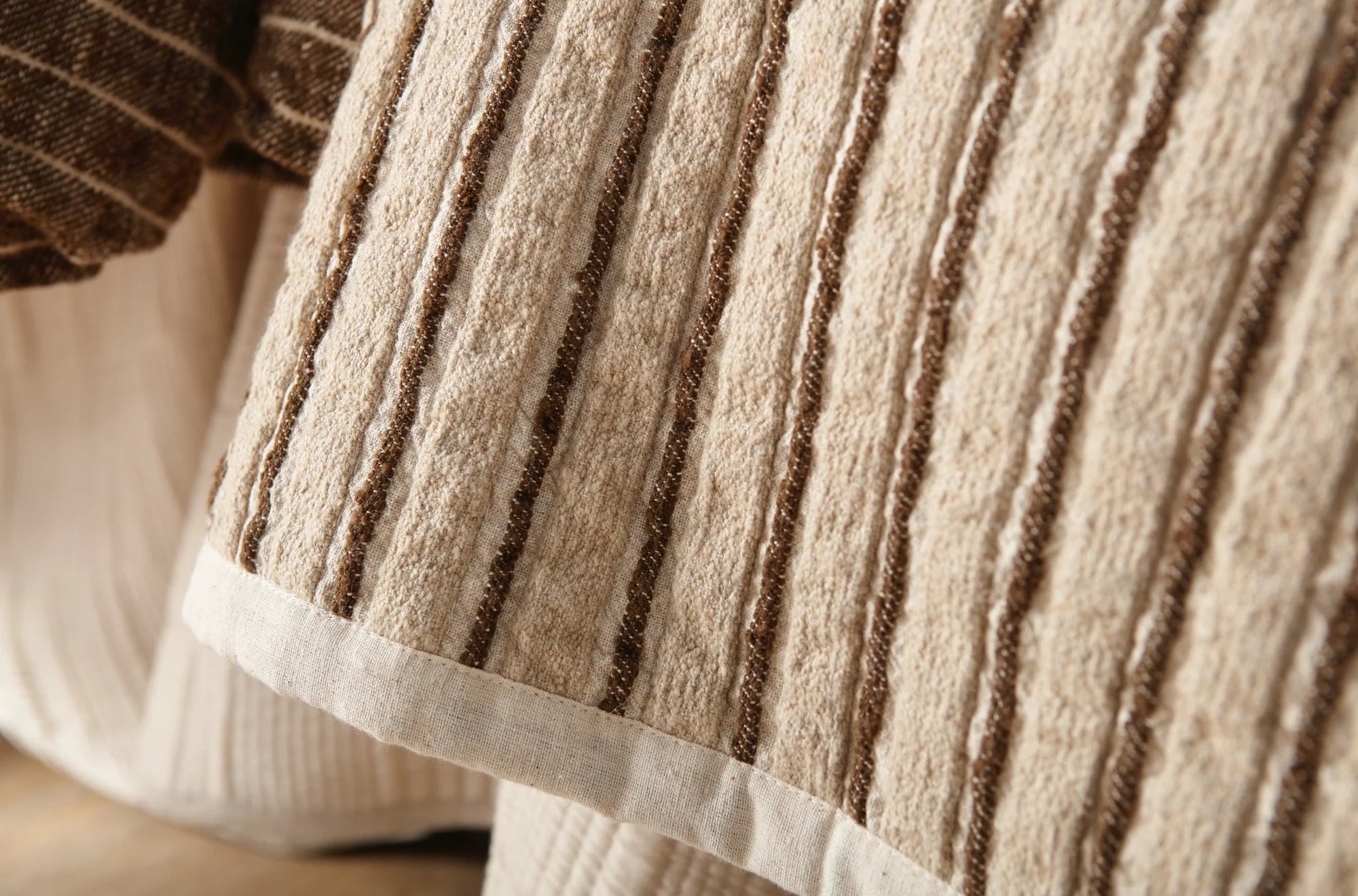Close-up of the Bonita Quilt King by Amity Home, featuring beige fabric with vertical brown textured stripes and a white border. The linen-cotton blend adds warmth and texture, perfect for a cozy addition to your home.