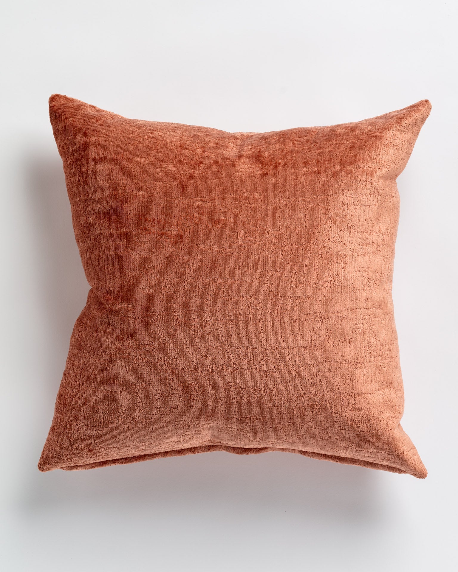 A soft, square-shaped Gabby Hamlet Terracotta Pillow 26x26 with a textured surface, photographed against a white background, encapsulating Arizona style.