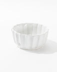 The Montes Doggett 5131 bowl no. 131 is a white ceramic piece featuring a scalloped edge and a glossy finish. This handcrafted bowl, with its shallow design that displays artisanal excellence, has a maker's stamp at the base and is photographed against a plain white background.