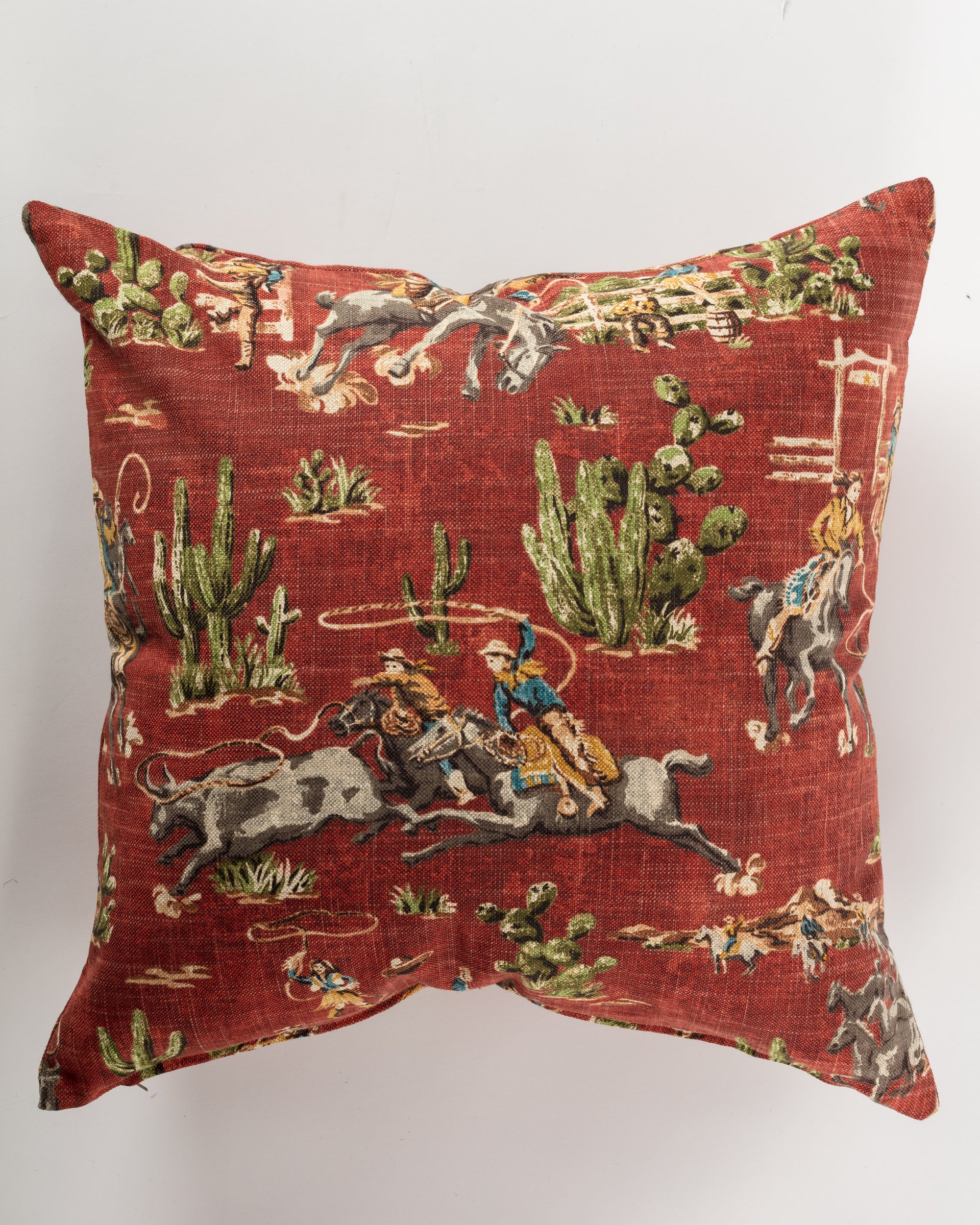 The Custom 2 Pillow 28x28 by Pindler adds a touch of luxury to your decor with its red background featuring a vintage Western-themed print. This custom-made square pillow showcases cowboys on horses, cattle, ropes, and cacti, embodying a rustic old-west aesthetic that brings charm to any space.